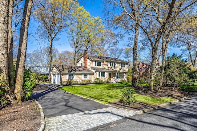 view of front of property featuring a chimney, a front lawn, and driveway