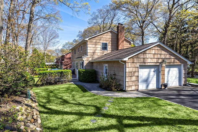 view of side of home with a lawn, a shingled roof, a garage, and a chimney