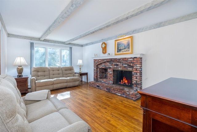 living room featuring beam ceiling, wood finished floors, and a fireplace