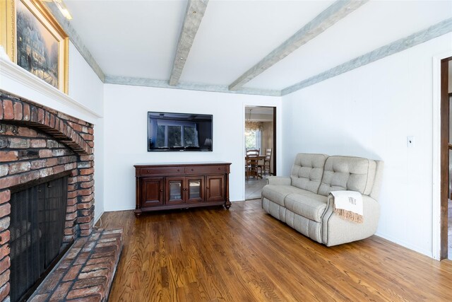 living room with wood finished floors, baseboards, beamed ceiling, and a brick fireplace