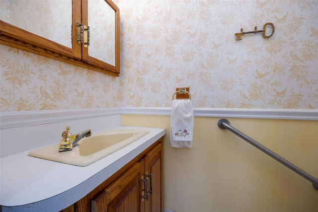 bathroom with wallpapered walls, a wainscoted wall, and vanity