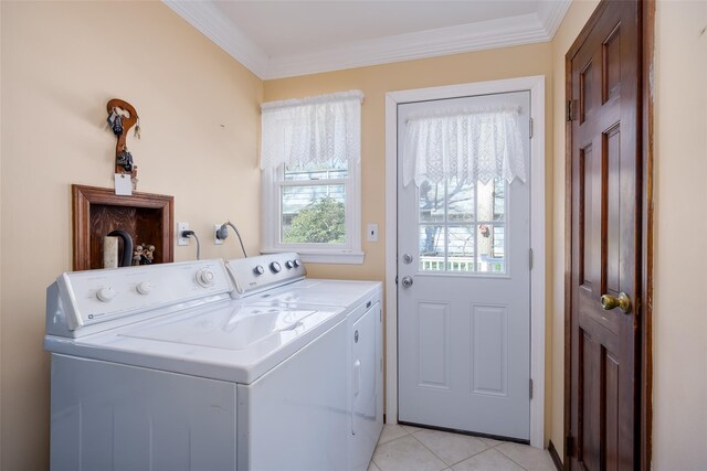 clothes washing area featuring light tile patterned flooring, ornamental molding, washing machine and clothes dryer, and laundry area