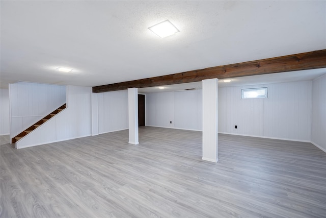 basement featuring baseboards, stairway, and wood finished floors