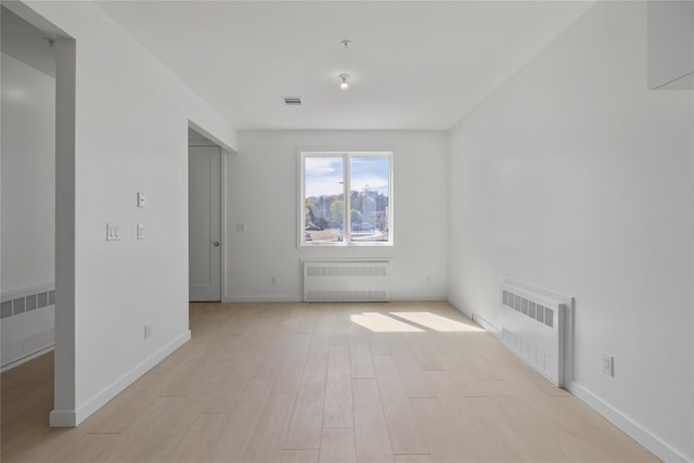 unfurnished living room with radiator heating unit, visible vents, baseboards, and light wood-type flooring