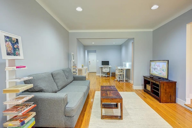living area with baseboards, crown molding, light wood finished floors, and recessed lighting