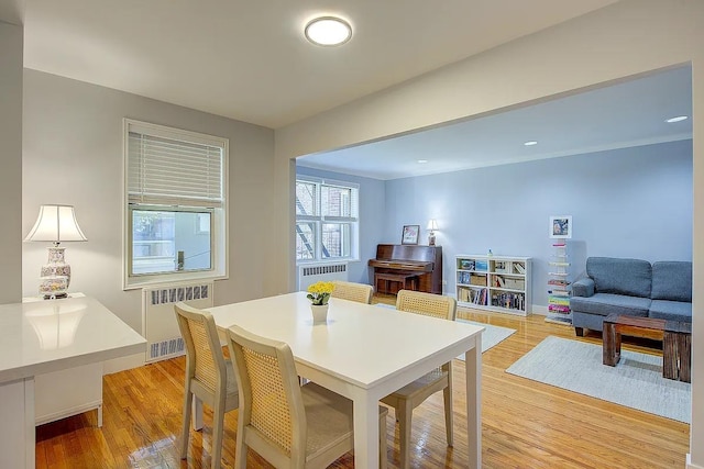 dining space with radiator heating unit and light wood-style floors