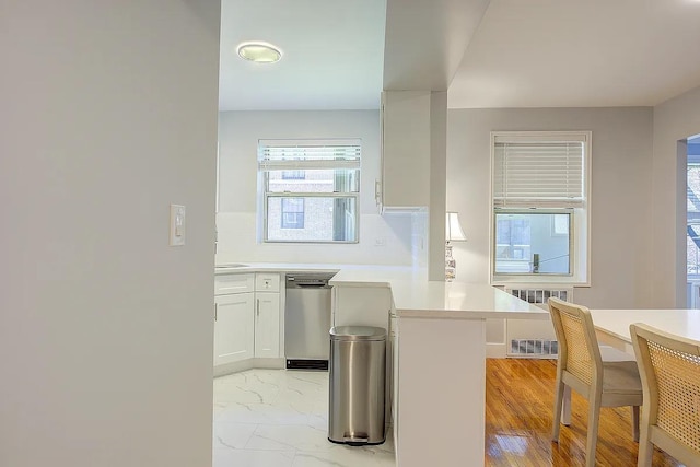 kitchen with a peninsula, tasteful backsplash, white cabinetry, dishwasher, and light countertops