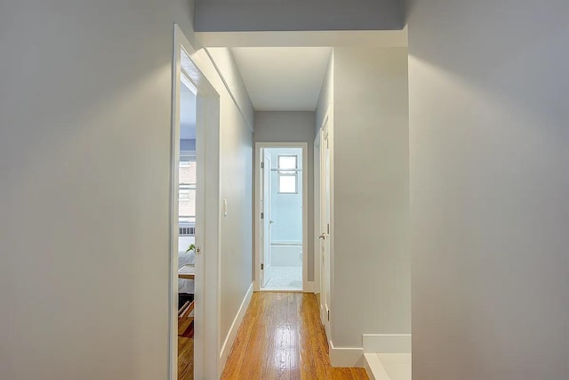 hall with light wood-style flooring and baseboards