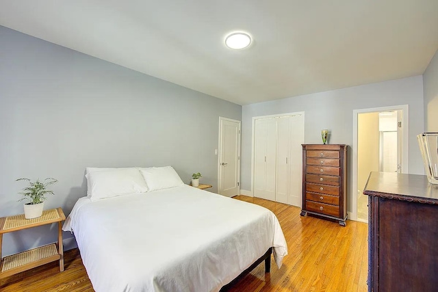 bedroom with a closet, light wood finished floors, and baseboards