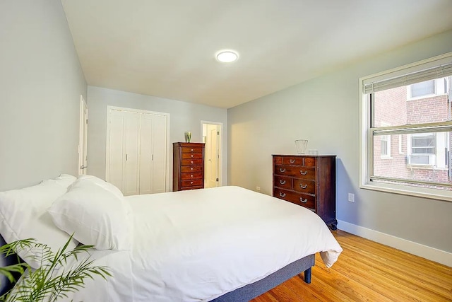 bedroom with light wood-style flooring, a closet, and baseboards