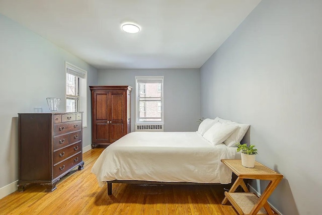 bedroom featuring light wood finished floors and baseboards