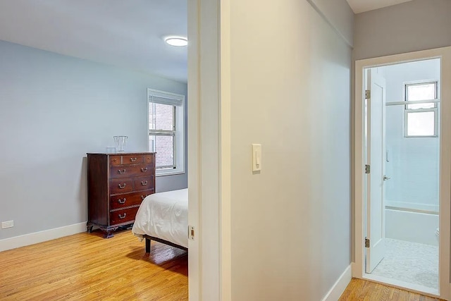 bedroom with light wood-type flooring, baseboards, and multiple windows