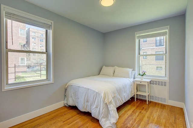 bedroom featuring radiator, baseboards, and multiple windows