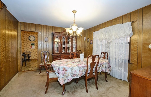 dining space featuring light colored carpet, wood walls, and a notable chandelier