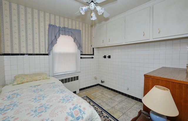 bedroom featuring wallpapered walls, light tile patterned floors, tile walls, ceiling fan, and radiator