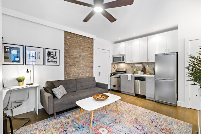 living area with wood finished floors, a ceiling fan, and baseboards