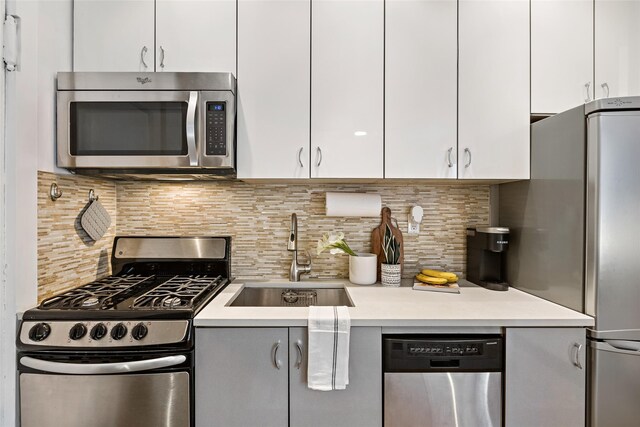 kitchen featuring decorative backsplash, appliances with stainless steel finishes, a sink, and light countertops