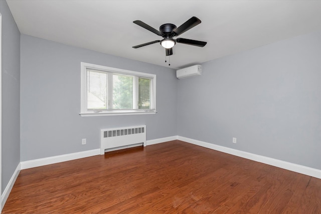 unfurnished room with wood finished floors, radiator heating unit, baseboards, a wall unit AC, and a ceiling fan