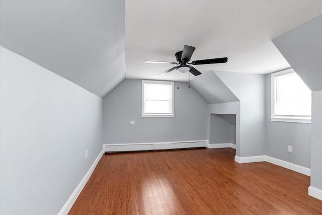bonus room featuring wood finished floors, vaulted ceiling, baseboard heating, ceiling fan, and baseboards