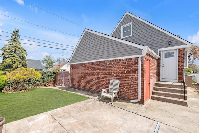 rear view of house featuring fence, a yard, a patio area, and brick siding