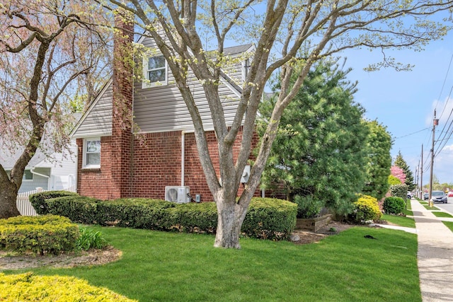 view of home's exterior featuring a lawn, a chimney, ac unit, and brick siding