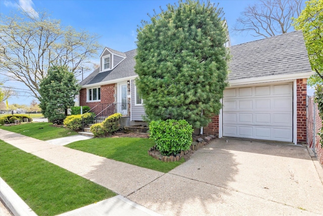 view of front of house featuring brick siding, a shingled roof, a front yard, and concrete driveway