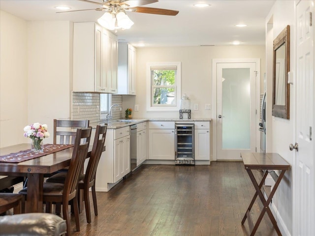 kitchen featuring beverage cooler, dark wood-style flooring, dishwasher, a sink, and a ceiling fan