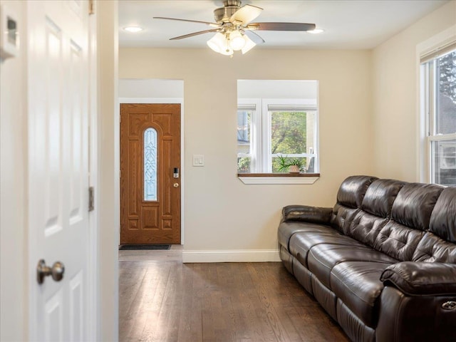living room featuring dark wood finished floors, a ceiling fan, and baseboards