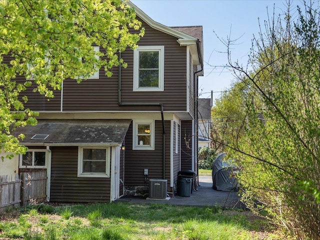 back of property featuring fence, roof with shingles, cooling unit, and a patio