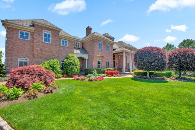 27 True Harbour Way W, Islip, NY 11795 - view of front of house featuring a chimney, a front yard, and brick siding