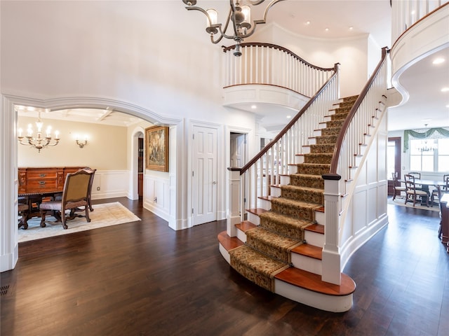 27 True Harbour Way W, Islip, NY 11795 - foyer with a chandelier, a decorative wall, stairs, dark wood-type flooring, and arched walkways