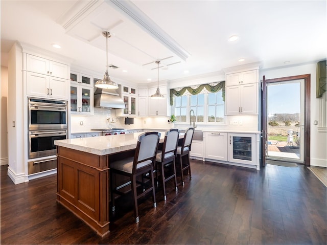 27 True Harbour Way W, Islip, NY 11795 - kitchen with stainless steel double oven, wine cooler, light countertops, wall chimney exhaust hood, and backsplash