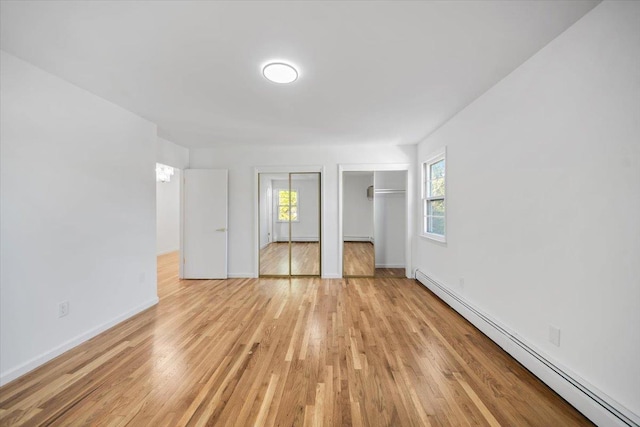10 Mohawk Rd, Yonkers, NY 10710 - unfurnished bedroom with a baseboard radiator, multiple windows, multiple closets, and light wood-style flooring