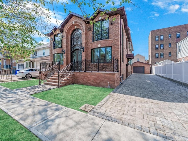 view of front of property with an outdoor structure, a front lawn, fence, brick siding, and a detached garage