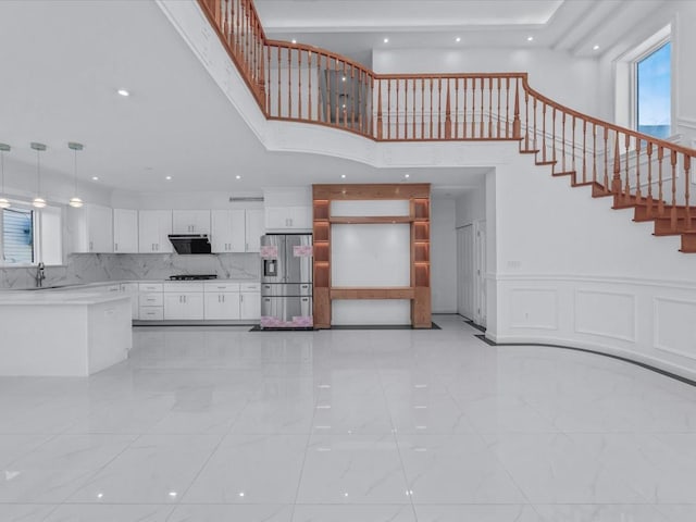 unfurnished living room featuring recessed lighting, a high ceiling, stairs, and marble finish floor