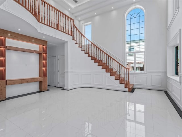 interior space with a high ceiling, a decorative wall, and a healthy amount of sunlight