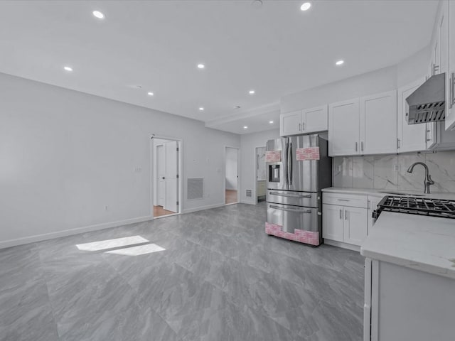 kitchen with open floor plan, stainless steel fridge, recessed lighting, wall chimney exhaust hood, and white cabinetry