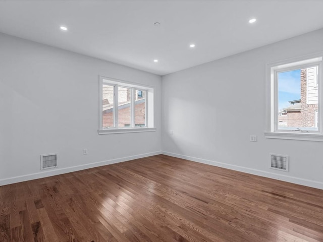 unfurnished room with visible vents, plenty of natural light, and wood finished floors