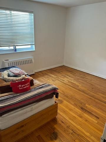bedroom with radiator, baseboards, and wood finished floors