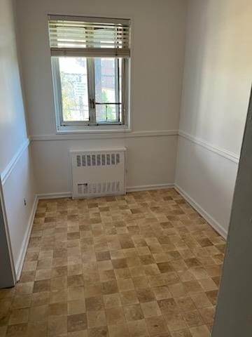 empty room featuring baseboards and radiator heating unit