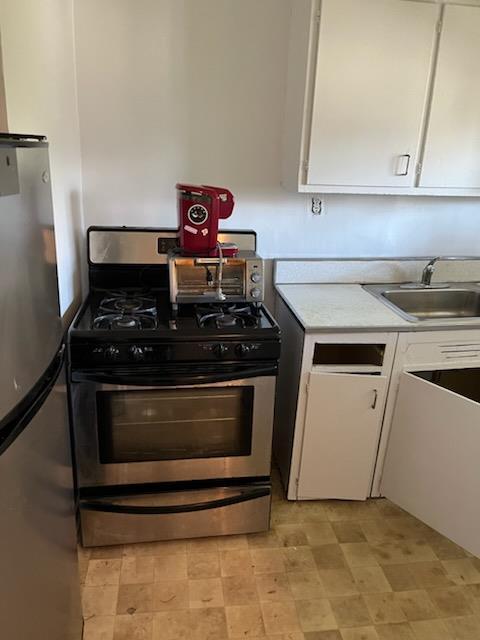 kitchen featuring light countertops, white cabinetry, stainless steel appliances, and a sink