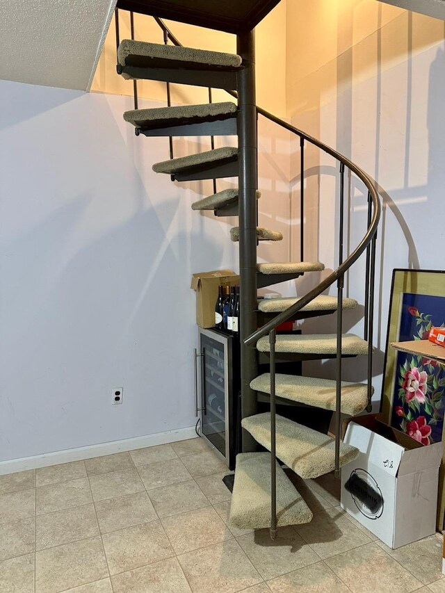 stairs featuring tile patterned flooring, baseboards, and beverage cooler