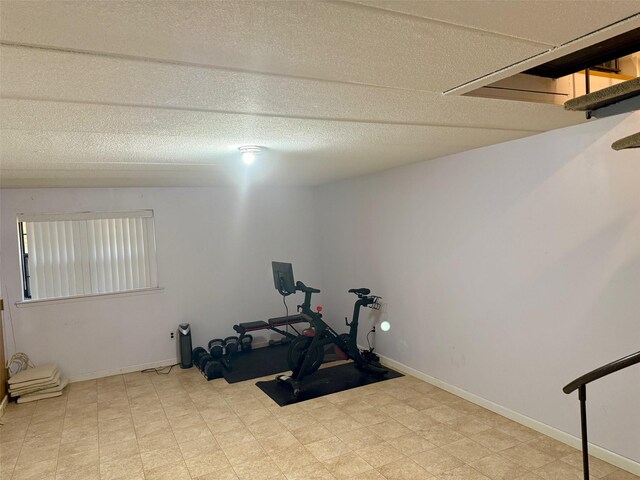 workout area with tile patterned floors, baseboards, and a textured ceiling