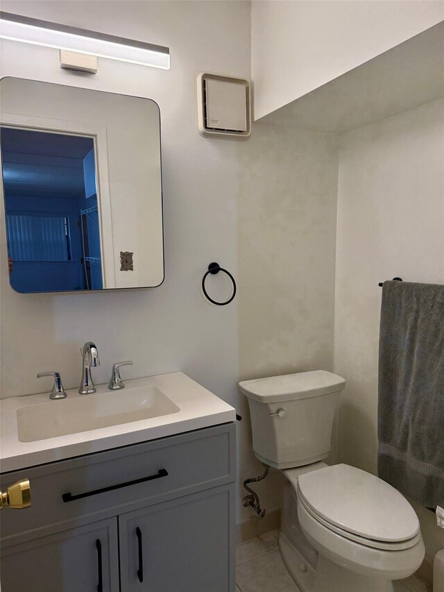 bathroom with toilet, vanity, and tile patterned floors