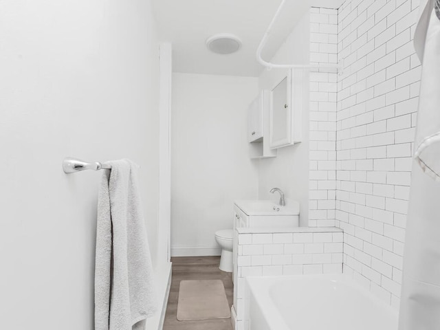 bathroom featuring toilet, a sink, baseboards, and shower / bathing tub combination