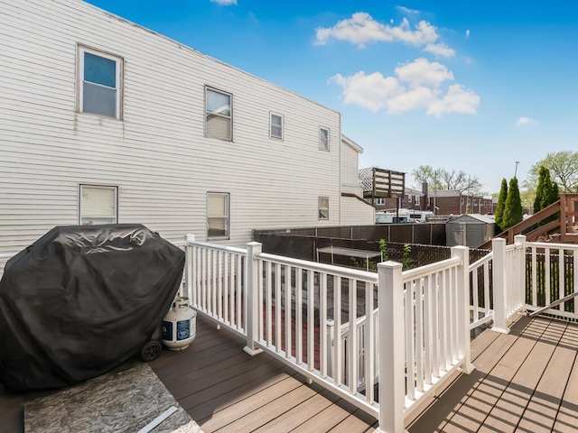 wooden deck featuring an outbuilding, a shed, a residential view, and a grill