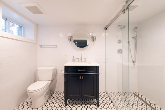 bathroom with a tile shower, toilet, visible vents, and vanity