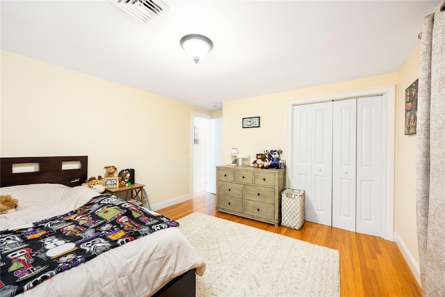 bedroom featuring light wood-type flooring, baseboards, visible vents, and a closet