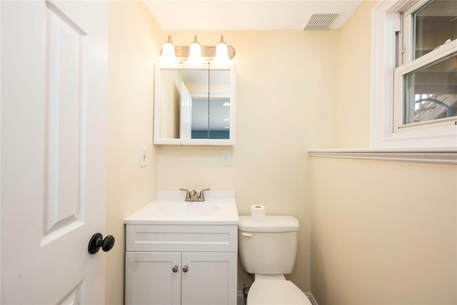 half bathroom with toilet, vanity, and visible vents