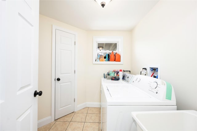 laundry room with baseboards, light tile patterned floors, a sink, washer and clothes dryer, and laundry area